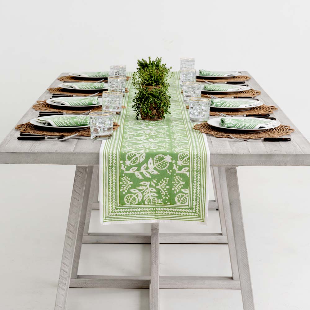 Green and white table runner decorating dinner table. 