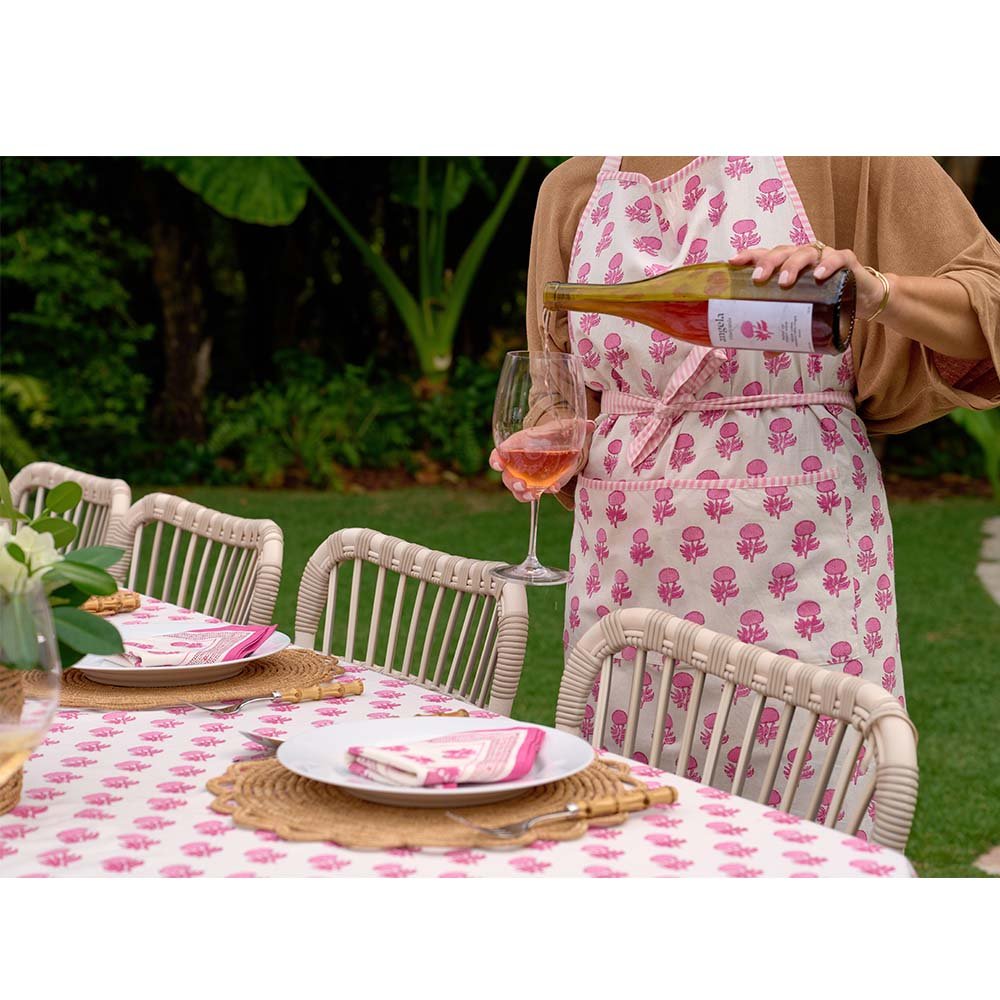 Model wearing rosé apron pouring rosé wine. 