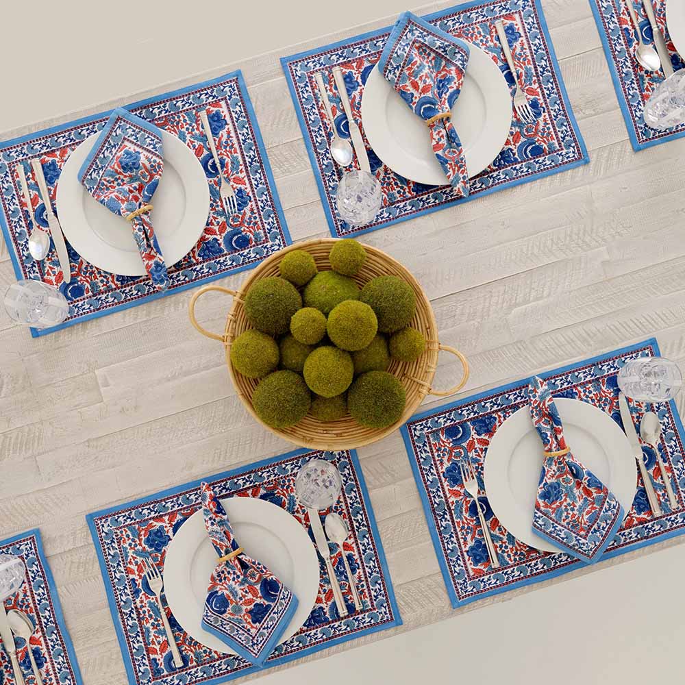 Floral pattern placemat with different hues of blues and paprika orange. 