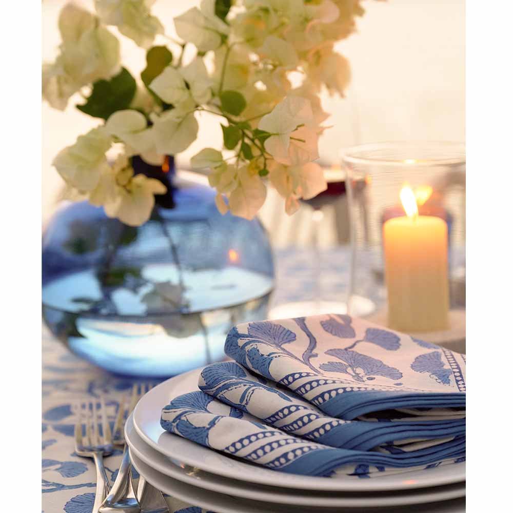 Stack of Ginkgo Blue napkins with flower arrangement. 