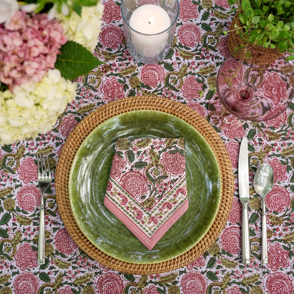 bohemian floral moss &amp; mauve napkin folded on green plate with wicker charger on table with matching tablecloth