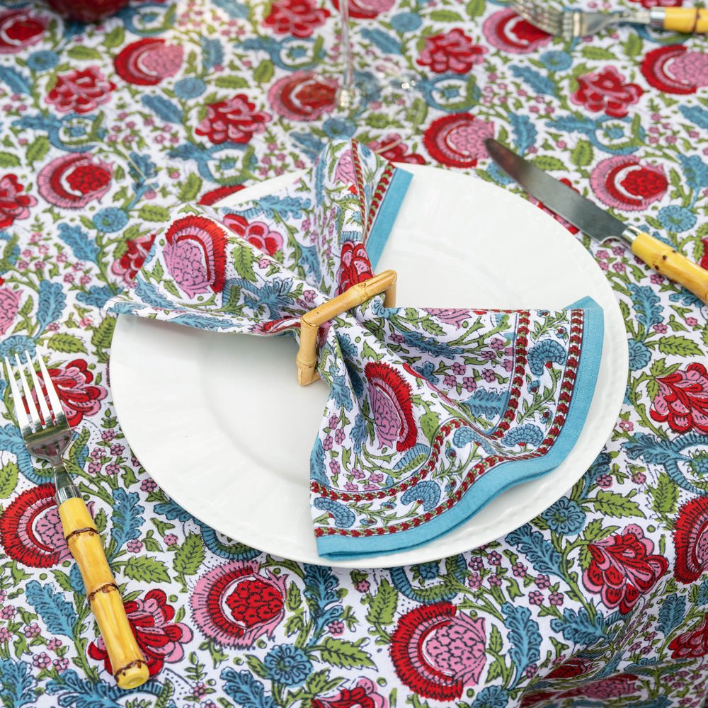 bohemian floral turquoise and cranberry napkin with square bamboo napkin ring on white plate with matching tablecloth underneath