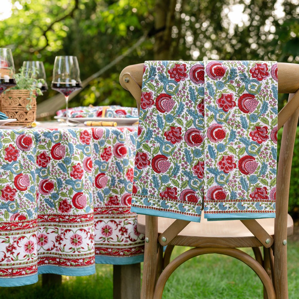 2 bohemian floral turquoise and cranberry tea towels hanging from wooden chair in front of table with matching tablecloth