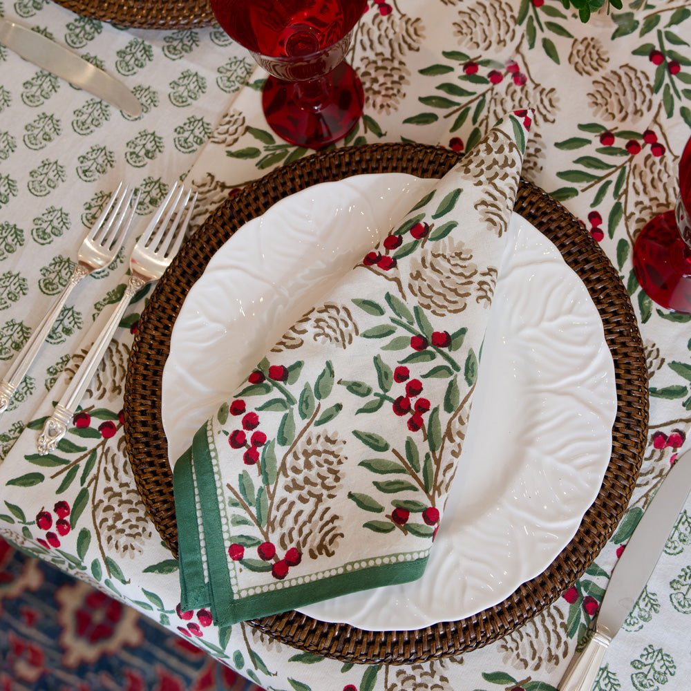 Christmas Garland napkin laying on plate with dark brown wicker charger on table with christmas garland table runner