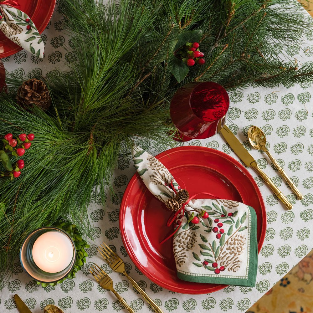 Christmas Garland Napkins on red plate with greenery and pinecones and berries