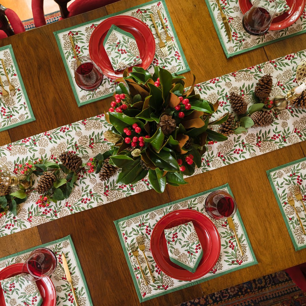 Christmas Garland placemats & napkins with red plates and matching table runner with pinecones and greenery