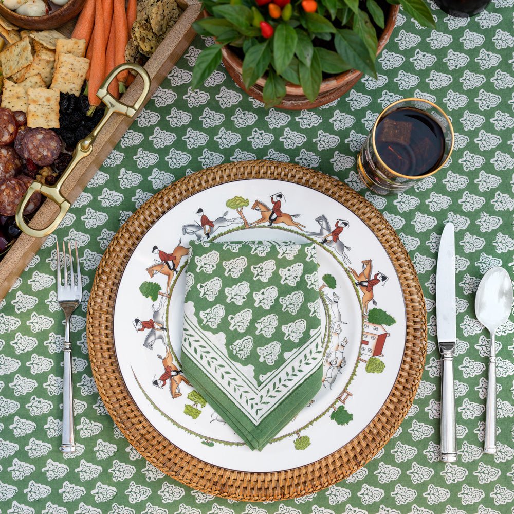 Pom Buti green napkin on plate and wicker charger on matching tablecloth