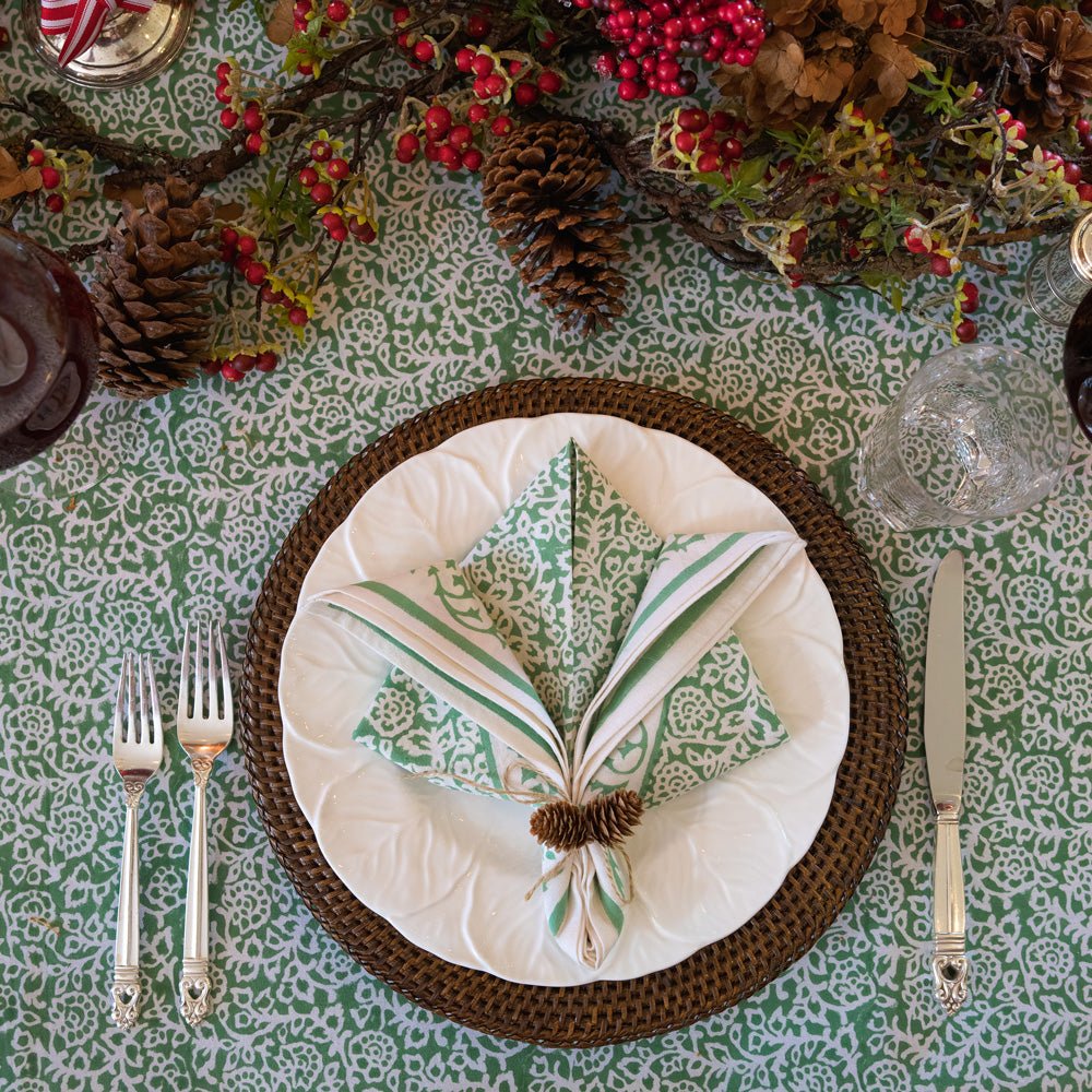 Tapestry Green Napkin on white plate with dark brown wicker chargers