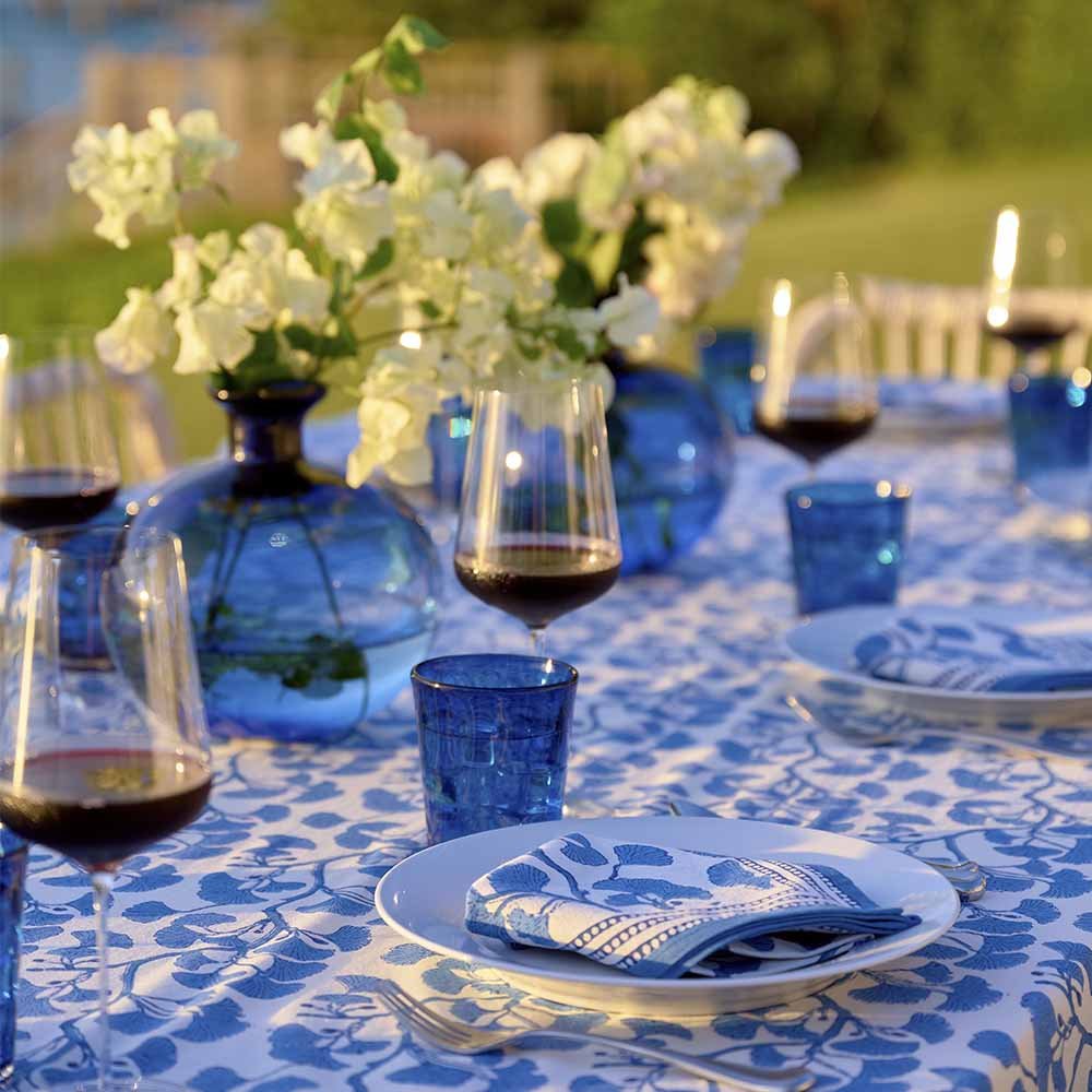 Dinner table with blue glasses and vases. 