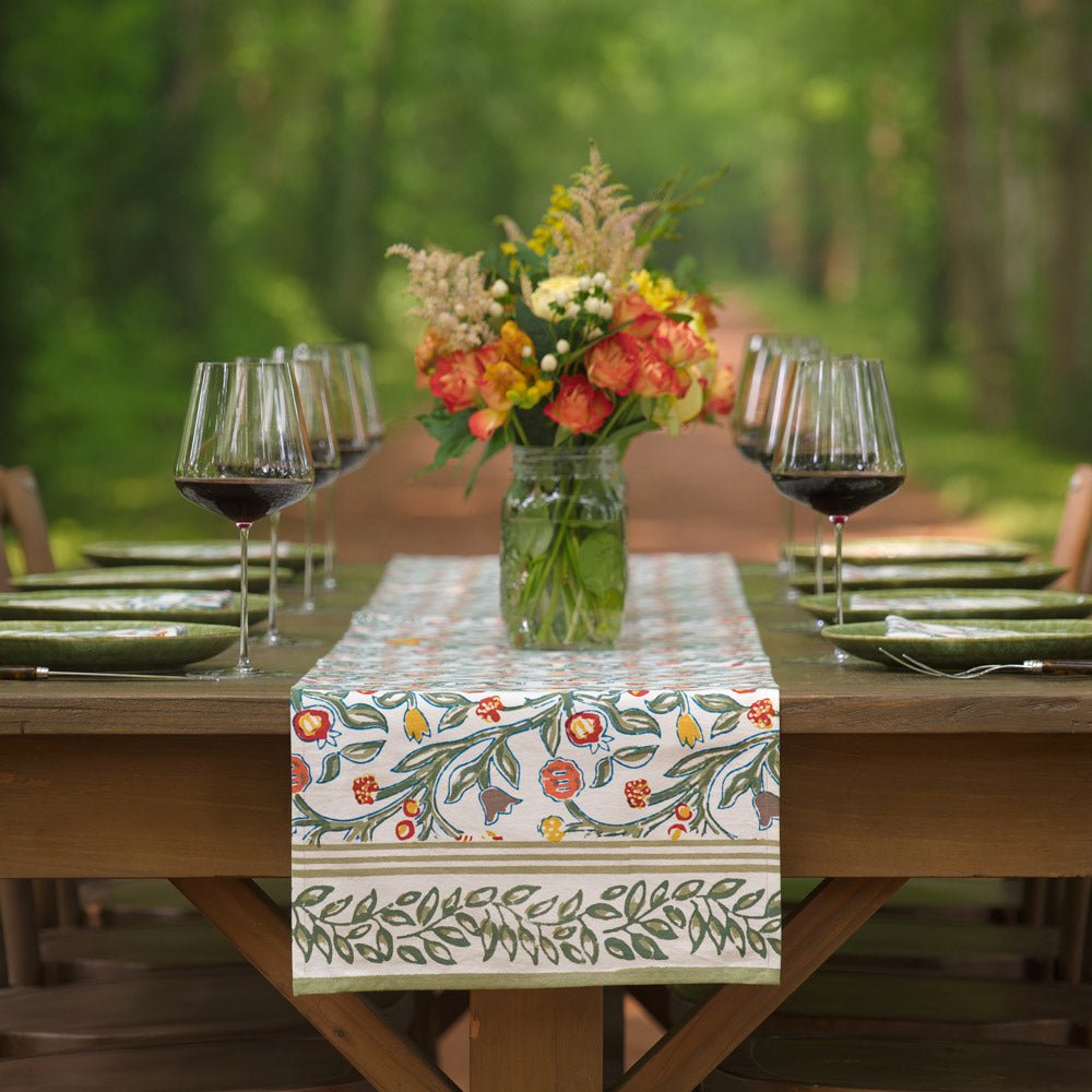 table runner with floral pattern in shades of sage green, crimson, marigold and deep orange