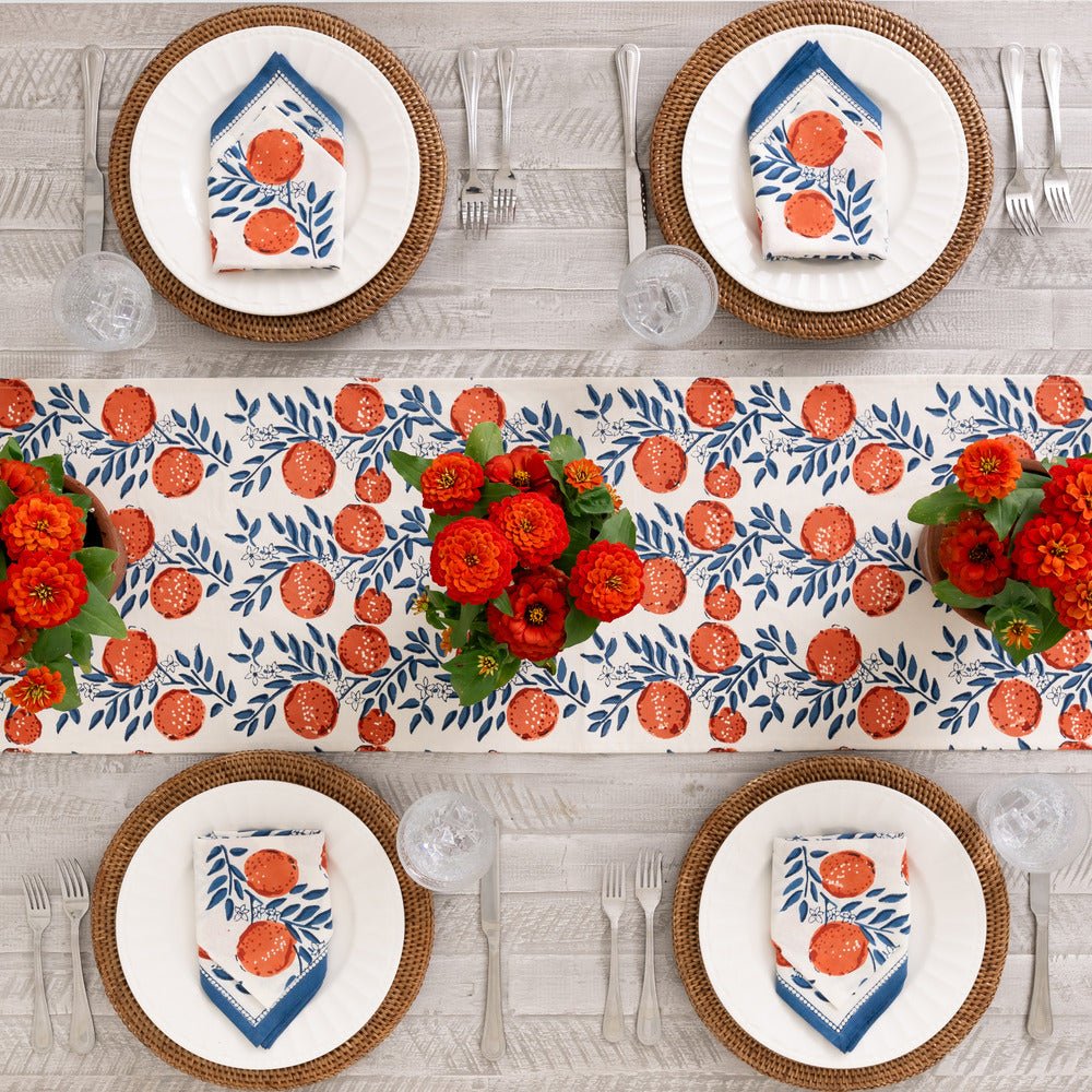 overhead view of table with orange grove table runner and matching napkins printed with blue vines and oranges