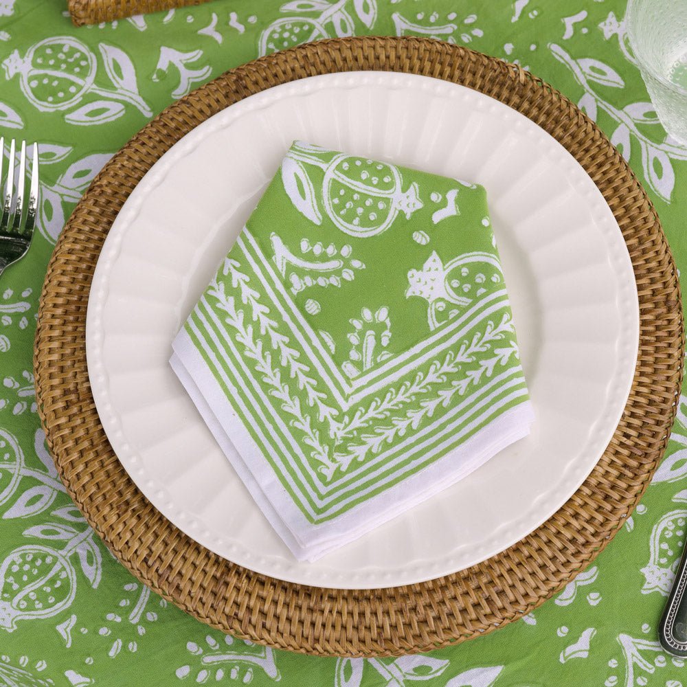 pomegranate green napkin on white plate with rattan charger and matching tablecloth