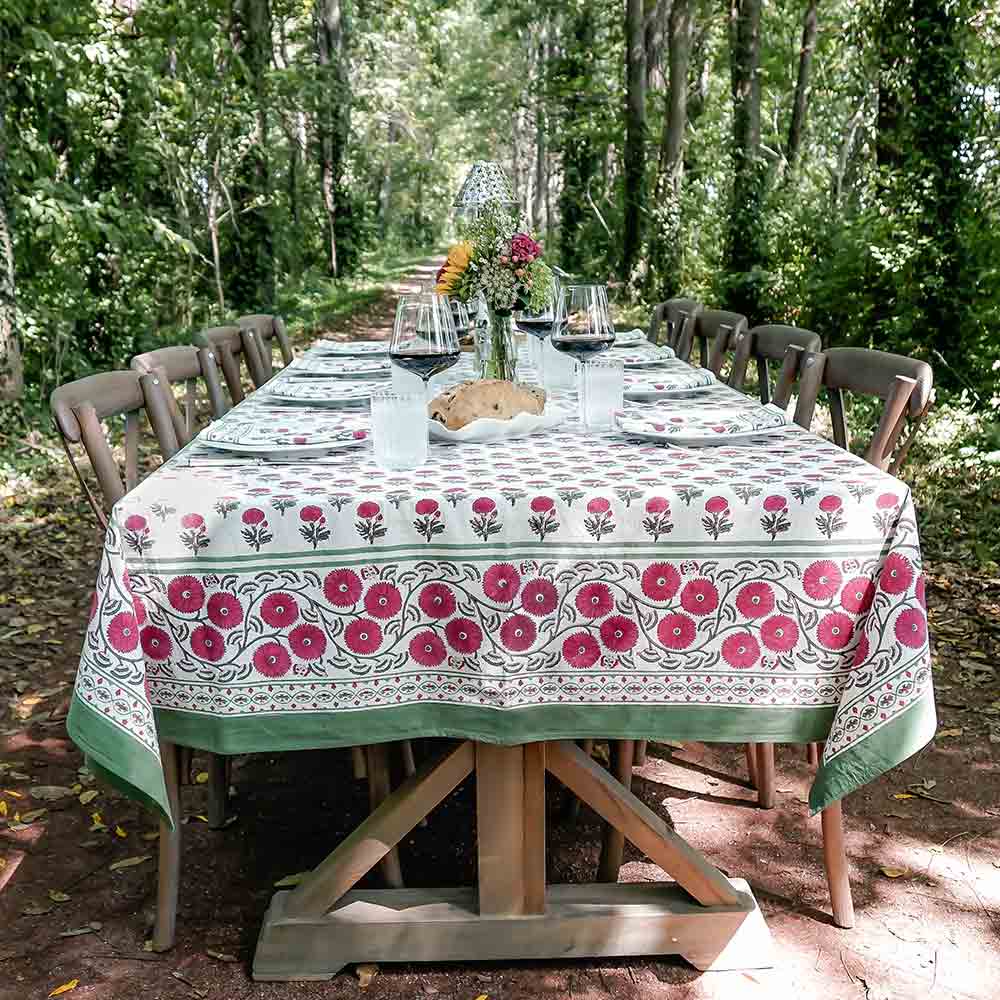 Outdoor table in the woods with Gaya Rose tablecloth and wine. 