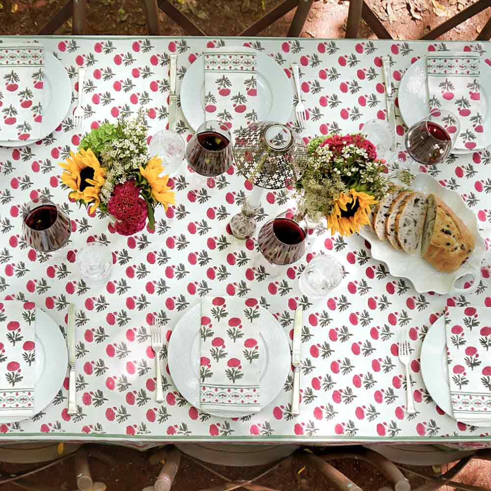 Outdoor dinner table with napkins and matching tablecloth with floral decor. 