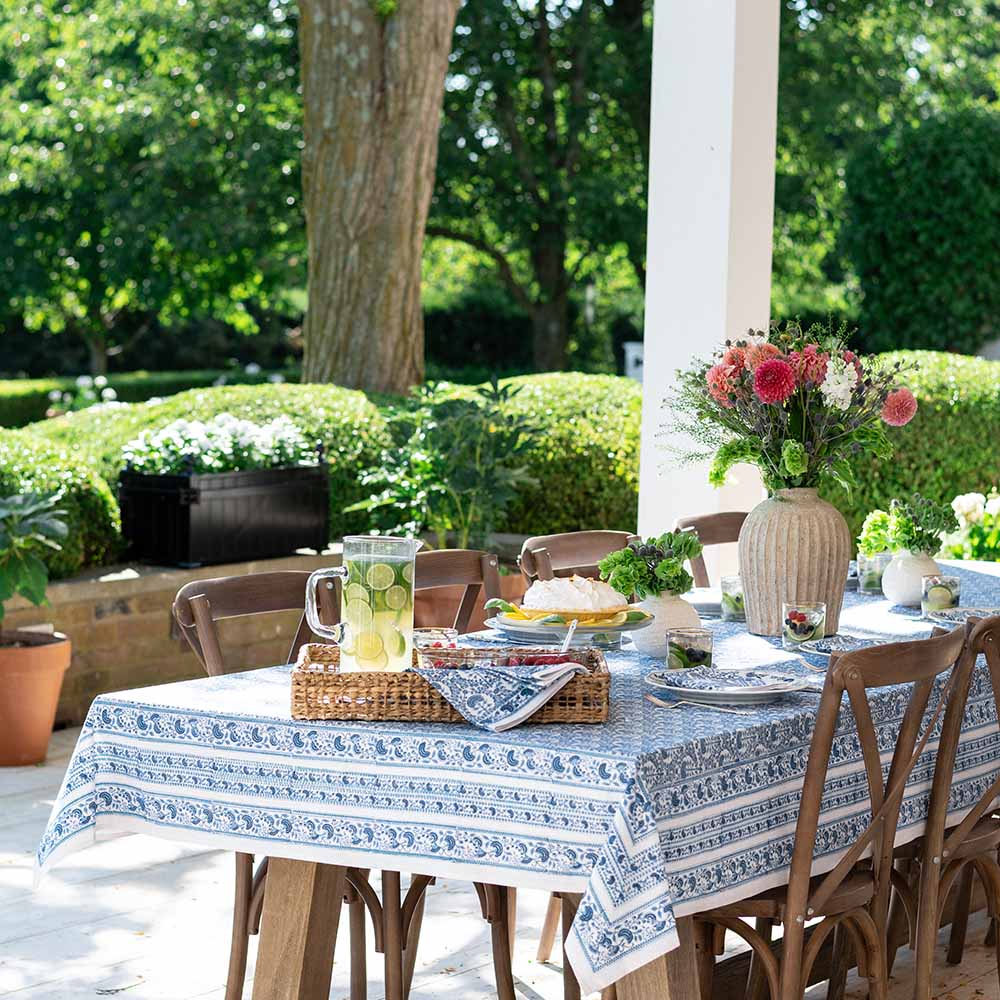 An outdoor table with lemonade, florals, and greenery compliment this richly blue tablecloth. 